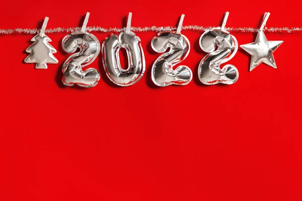 Новий рік 2022 кількість срібних кульок і м'які іграшки формуються як ялинка і яскрава зірка, що звисають над фоном червоної тканини. Щасливі свята рамка — стокове фото