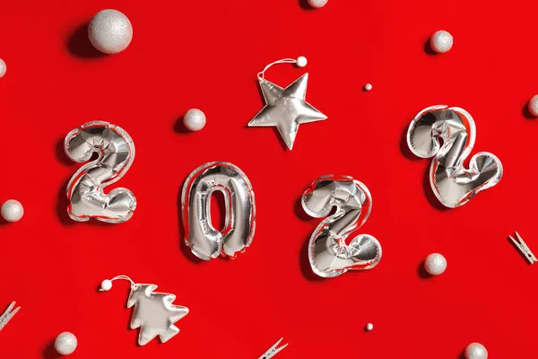Новий рік 2022 кількість срібних кульок і м'яких іграшок у формі ялинки і яскравої зірки, прикрашені кульки на фоні червоної тканини. Зимові святкові листівки — стокове фото