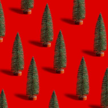 Kırmızı arka planda yeşil parlayan Noel ağacı deseni. Kontrast Parlak Yeni Yıl Mini şenlik köknarı, xmas dekor süsü, kış tatili konsepti. Şenlikli duvar kağıdı.