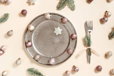 Noel tabağı, şenlik sofrası konsepti, parlak küçük toplar metal tabakta bej pembe renk, bıçak, çatal. Yılbaşı yemeği geçmişi, xmas süslemesi, yeşil köknar ağacı, yaratıcı düzlük