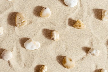 Kum üzerinde çakıl taşı deniz taşlarıyla desen. Doğal taş nötr bej sarı renk, tek renkli tonlar. Yaz için minimum tasarım geçmişi, meditasyon ve rahatlama konsepti, spa. Yukarıdan görüntüle