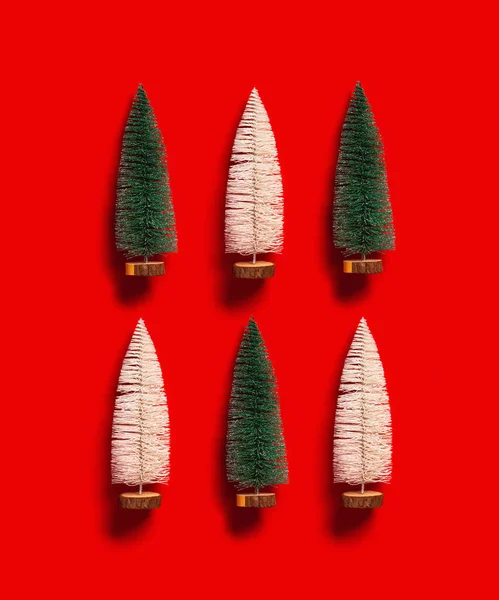 正方形に刻まれた赤の背景にクリスマスツリーの緑と白の色を持つパターン ミニお祝いモミ 休日の冬やクリスマスのコンセプトと明るい最小限の新年の挨拶カード トップ表示 — ストック写真