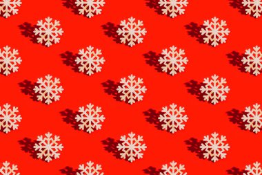 Kırmızı arka planda doğal malzemeden yapılmış kar tanecikli oyuncaklarla Noel düzeni. Yılbaşı süsleri, güneş ışığından gelen gölgelerle.