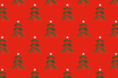 Çam dallarından gelen yeşil Noel ağacı ve kırmızı zemin üzerinde yılbaşı ağacı olan yaratıcı bir Noel deseni. Minimum kış tatili