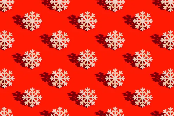 Kırmızı arka planda doğal malzemeden yapılmış kar tanecikli oyuncaklarla Noel düzeni. Yılbaşı süsleri, güneş ışığından gelen gölgelerle.