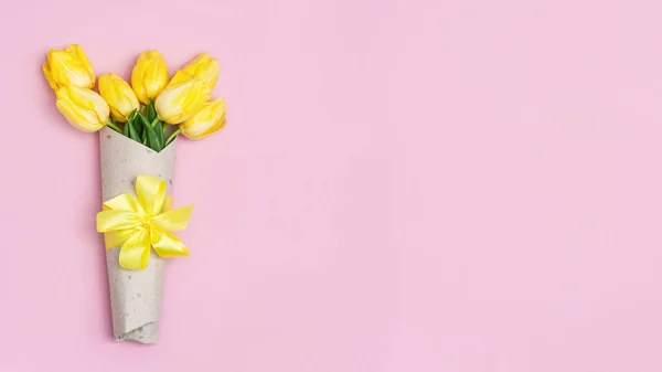 リボン付きクラフト紙の新鮮な黄色のチューリップ コピースペースで明るい春の花を咲かせます 3月8日の母の日の背景 女への贈り物だ — ストック写真