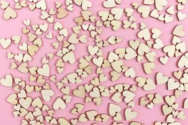 Pembe kağıt yüzeyinde küçük tahta kalpler olan tebrik kartını kutlayın. Aşk konsepti. Üst görünüm ve düz uzanma.