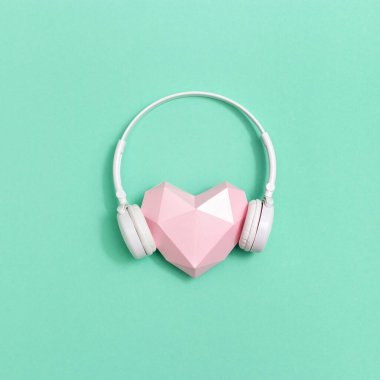 Beyaz kulaklıklı, pembe sesli kağıt kalp. Müzik festivalleri, radyo istasyonları, müzik severler için konsept. Müzikle yaşa. Asgari biçim.