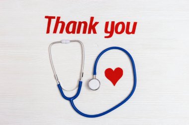 Stetoskop mavi, kırmızı kalp ve metin beyaz ahşap arka planda fotokopi alanı ile birlikte teşekkürler. Sağlık ve tıbbi konsept. Dünya Sağlık Günü. Yukarıdan görüntüle.