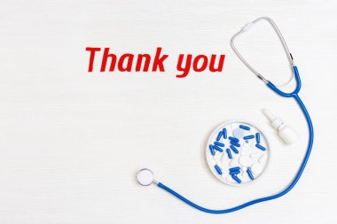 Stetoskop mavi renkli, haplar ve metin fotokopi alanı olan beyaz ahşap arka planda teşekkürler. Sağlık ve tıbbi konsept. Dünya Sağlık Günü. Yukarıdan görüntüle.