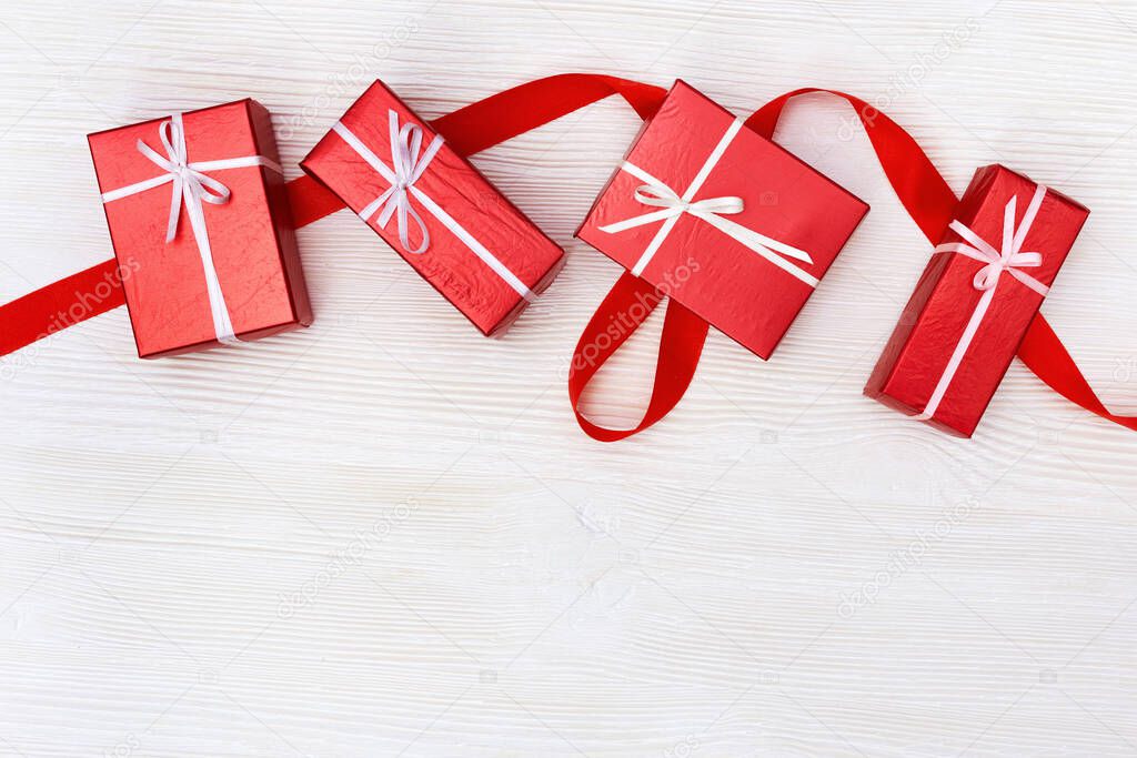 Presents boxes red colored on white wooden background. Copy space for your text. Greeting card, holiday concept.