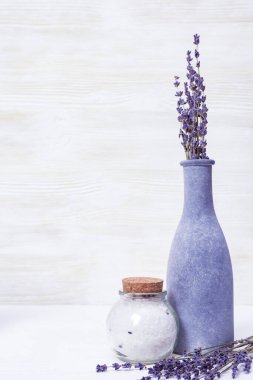 Mor lavanta ve deniz tuzu. Doğal sağlık hizmeti konsepti. Ahşap arka planda lavantalı şişeler. Seçici odak.