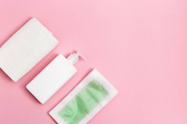 Tüy dökücü için tek kullanımlık balmumu bantlar, vücut nemlendirici ve pembe arka planda fotokopi alanı olan beyaz pamuk havlu. Saç çıkarma prosedürü. Üst görünüm.