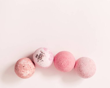 Doğal banyo bombaları, deniz tuzu, gül yağı ve bitkisel malzemelerle kaplıca ürünleri. Güzellik ve vücut bakımı için doğal kozmetik, bitkisel ilaçlar, pembe arka plan, kopyalanma alanı