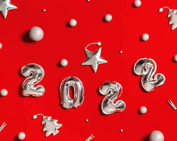 Новий рік 2022 кількість срібних кульок і м'яких іграшок у формі ялинки і яскравої зірки, прикрашені кульки на фоні червоної тканини. Зимові святкові листівки — стокове фото