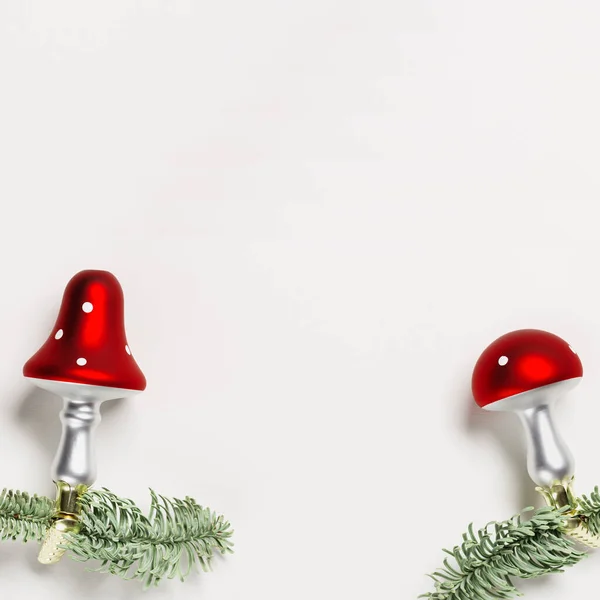 Julen botaniska prydnader flyga agarisk svamp med röd hatt och vita prickar, på naturliga gröna julgran grenar på vit bakgrund med kopia utrymme. — Stockfoto