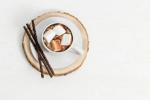 Xícara branca de chocolate quente com marshmallows e paus de chocolate no fundo de madeira branco com espaço de cópia. Vista superior. — Fotografia de Stock