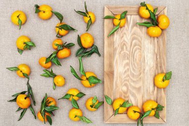 Kırsal arka planda yaprakları olan mandalina portakalları. Kopya alanı olan tahtadan meyveler..