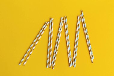 Parlak kağıt, sarı arka planda altın çizgili ve fotokopi alanı olan pipetler içiyor. Parti ya da doğum günü kavramı.