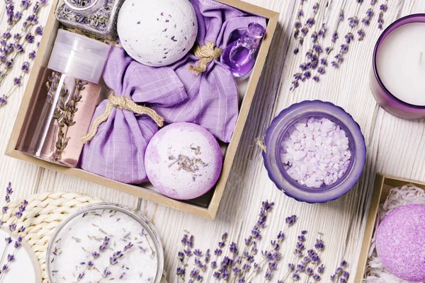 Produk dengan minyak lavender esensial sebagai kotak hadiah buatan tangan, bom mandi, semprotan lavender dan sachet di atas meja kayu. Pemberian cermat, Kosmetik aromaterapi alami untuk perawatan tubuh — Stok Foto