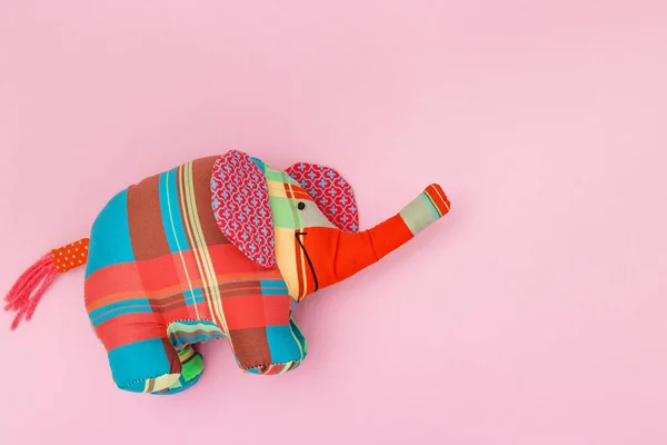 玩具象，用粉红色背景的彩色织物缝制而成，有复制空间。用手工制作的动物很可爱. — 图库照片