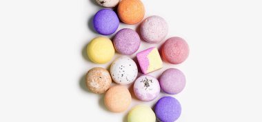 Beyaz kâğıt üzerinde renkli banyo bombaları olan desen. Rahatlamak ve aromaterapi için gerekli yağ ile banyo topları. Vücut bakımı doğal ürünler. Kaplıca için renkli kozmetik bombası. Üst görünüm