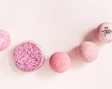 Natural bath bombs and sea salt with rose essential oil, spa products with dry herbal ingredients. Natural cosmetic for beauty treatment and body care, herbal medicine, pink background