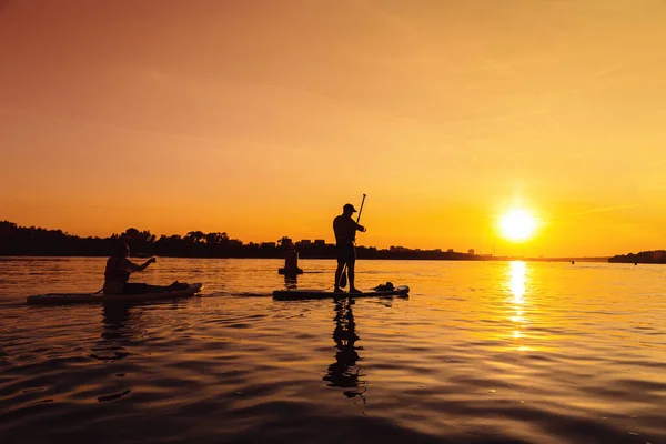 Silhouette man standing up on sapboard. Man ride boat on river at sunset with beautiful view — 스톡 사진