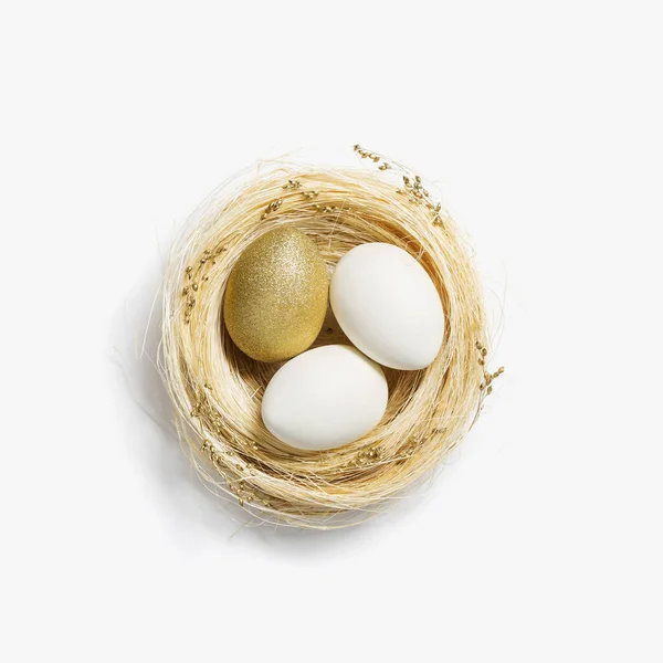 Velikonoční zlatá vejce v slámovém hnízdě na bílém pozadí. Módní zlaté vejce na jarní prázdniny. Top view jiskra Velikonoce minimální kreativní kompozice. Veselé Velikonoční jarní prázdniny — Stock fotografie