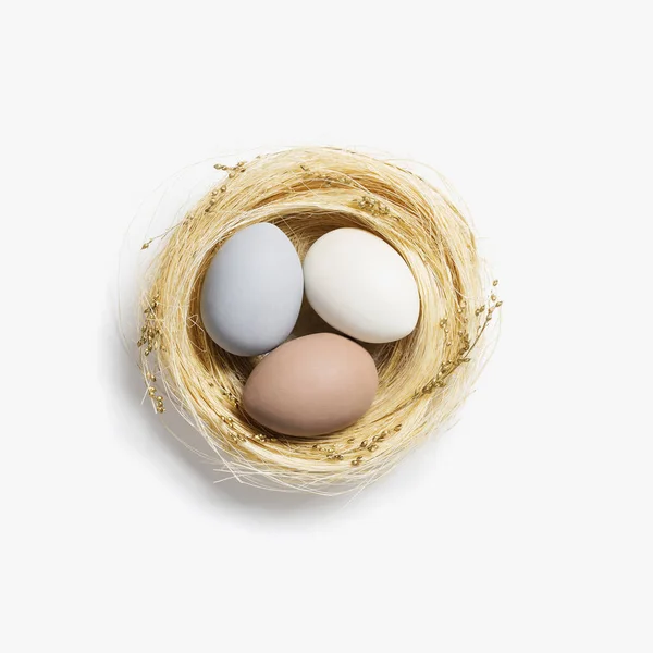 Pasen Neutraal gekleurde eieren in stro nest op witte achtergrond. Trendy pastel kleur ei voor de voorjaarsvakantie. Top view Paasmatige samenstelling Vrolijk paasweekend — Stockfoto