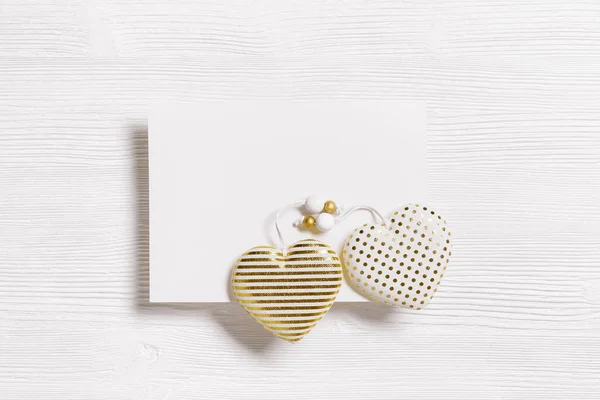 Corazones hechos a mano de tela de algodón con rayas de color dorado o puntos y papel blanco vacío para el mensaje de amor sobre fondo de madera blanca. Tarjeta de felicitación del día de San Valentín. Postal de San Valentín — Foto de Stock