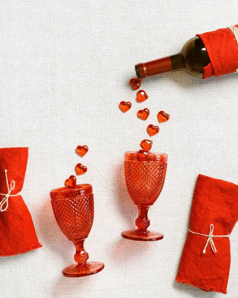 Концепція святковості для Валентинів 14 день фебрутальна, святкова таблиця, червоні серця падають з пляшкового вина в червоних склянках вина, лляні серветки на тканині фону, копіювальний простір — стокове фото