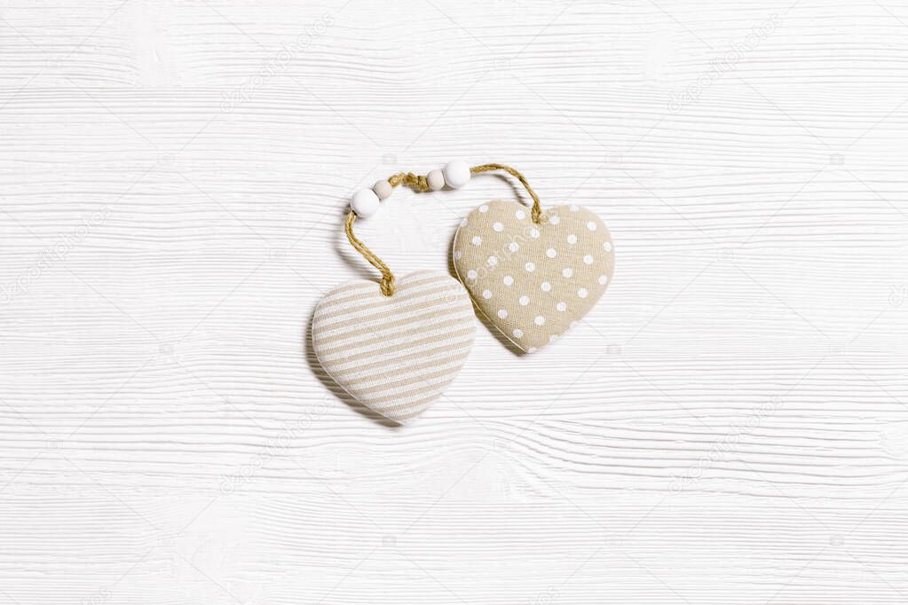 Valentines day concept. Two soft toy hearts from linen cloth with golden color striped or dots on white wooden table. Valentines Day background with copy space. Theme of love, top view