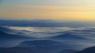 Renkli dağ tepeleri kış akşamında gün batımında tonsal perspektifle. Gornaya Shoria 'daki soyut panoramik manzara, Rusya' daki Sheregesh kayak merkezi Foggy Dağları doğa arka planı