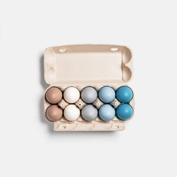 Paaseieren pastel gekleurd in eierdoos op lichte achtergrond met kopieerruimte. Minimaal paasfeest concept, geverfd kippenei met kleurverloop van blauw tot beige gekleurd in kartonnen verpakking — Stockfoto