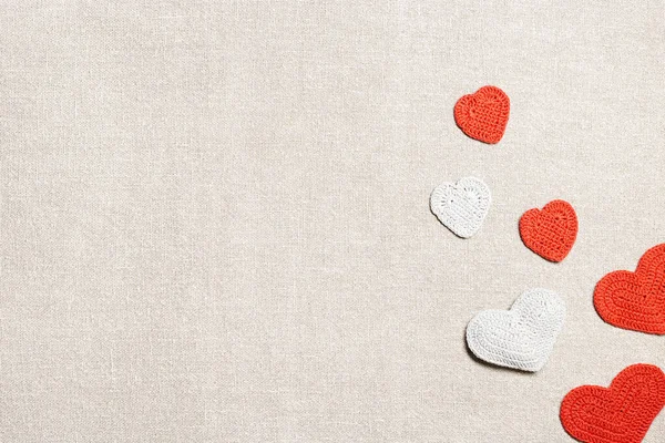 バレンタインデーの背景、ニットハートバレンタイン、リネン布テーブルの上に手作りの赤いかぎ針編みの心、ロマンスの休日のための手作りの贈り物、愛の象徴。コピースペース付きのお祭りカード。トップ表示 — ストック写真
