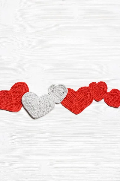 Valentýnský koncept, pletená srdce valentýnský, ručně dělané červené háčkované srdce na bílém dřevěném stole, diy dárek na romantickou dovolenou, symbol lásky. Slavnostní pozadí s kopírovacím prostorem. Horní pohled — Stock fotografie