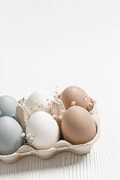 Close up Paaseieren pastelkleurig in eierdoosje versierd met bloemetjes. Minimaal paasfeest concept, geverfd kippenei met beige, witte, grijze kleuren in kartonnen verpakking. Selectieve focus — Stockfoto