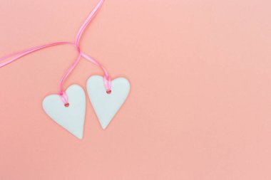   Romantizm konsepti. İki beyaz kalp ve pembe kurdele pembe renkli kağıt pastel. Kalpler birbirine bağlı. Sevgililer Günü geçmişi. Asgari biçim.