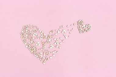 Büyük olandan küçük kalp çıkar. Yeni aşkın doğuşu. Aşk kavramı. Pembe arka planda bir sürü küçük tahta kalp. Düz yatıyordu.