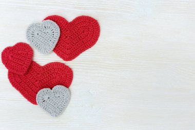 Kabarık kalpli tebrik kartı, ahşap arka planda yazı için yer var. Parlak kırmızı ve gri tekstil kalpleri. Üst görünüm.