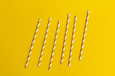 Parlak kağıt pipetler, sarı arka planda fotokopi alanı olan kokteyller için. Yaz tatili konsepti. Minimal biçim düzlüğü.