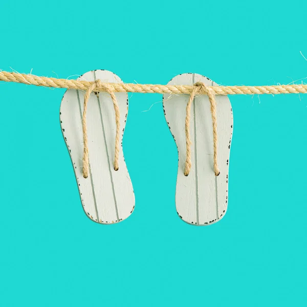 Verão férias conceito mínimo com sapatos de praia chinelos pendurados na corda com fundo turquesa. — Fotografia de Stock