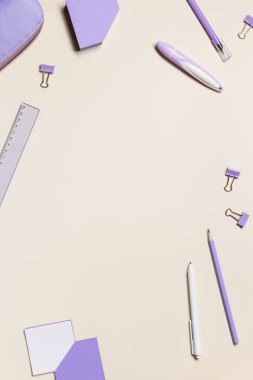 Okul kırtasiyesinin dairesi son derece moda renkteydi. Okul konseptine geri dönelim, defter, not, kalem, kalem, kalem kutusu, pastel bej arka planda ataçlar. Ofis ekipmanları, üst görünüm