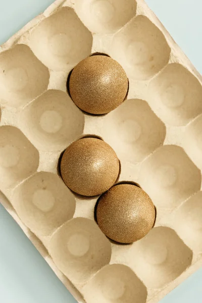 Painted Easter eggs gold colored in eggs box. Minimal easter concept. Beige monochrome photography. — Stock Photo, Image