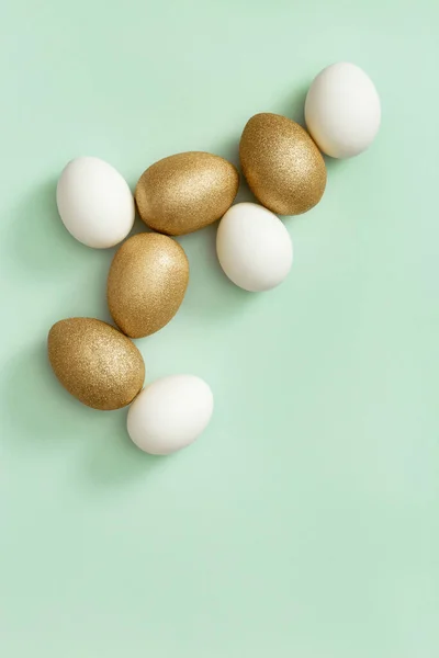 Украшенные пасхальные золотистые и белые яйца на зеленом фоне. Пасхальная открытка, открытка — стоковое фото