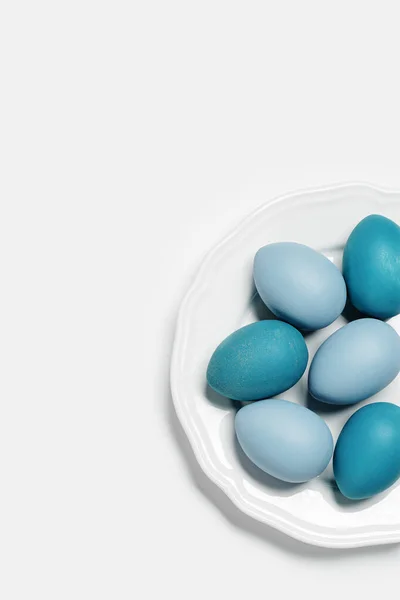 Dyed Easter eggs pastel colors blue, gray, beige on round white plate. Happy Easter holiday concept, celebration food, decorated chicken egg, neutral trendy colored card. Top view table — Stock Photo, Image