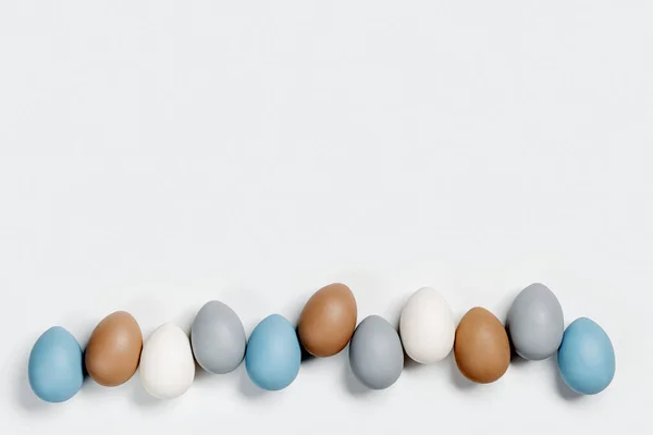 Geverfd paaseieren pastel kleuren blauw, grijs, beige in rij op witte achtergrond. Fijne paasvakantie, feestelijk eetconcept, kippenei neutrale trendy kleur. Bovenaanzichtstabel — Stockfoto