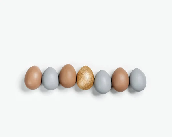 Dyed Easter eggs pastel colors gray, beige and golden in row on white background. Happy Easter holiday, celebration food concept, chicken egg neutral trendy color. Top view table — Stock Photo, Image