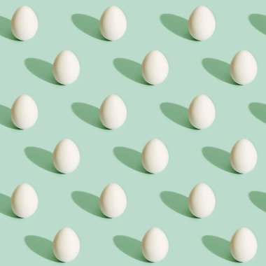 Açık yeşil kağıttaki beyaz yumurtaların pürüzsüz deseni. Yemek konsepti. Paskalya baskısı.